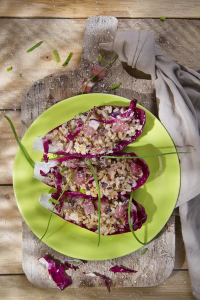 Båt av brunt ris med röda radicchio och speck — Stockfoto