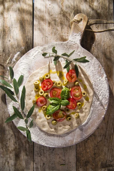 Raw pizza with tomato and olives — Stock Photo, Image