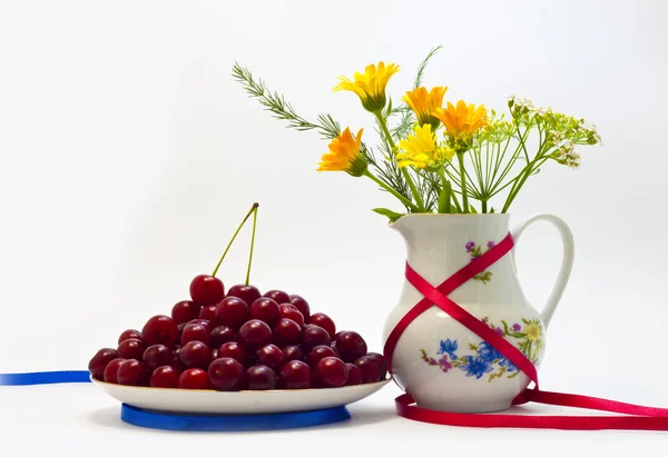 Stillleben von Kirschen und Blumen in einer Vase auf weißem Hintergrund — Stockfoto