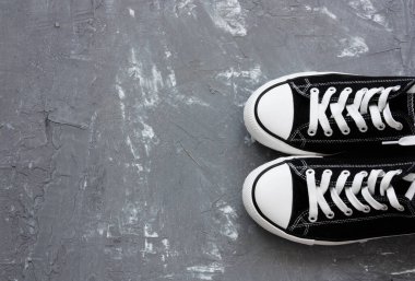 Gri arkaplanda bir çift siyah beyaz spor ayakkabı