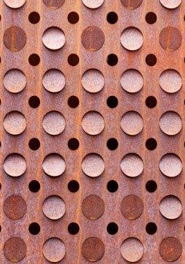 Paslı ve simetrik yuvarlak delikli eski metal levha, grunge tarzı endüstriyel dekor. Dikey resim.