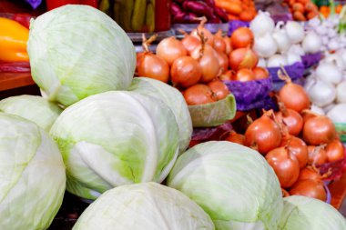 Beyaz lahana, altın ve beyaz soğanların arka planına yakın çekim pazar tezgahındaki sebze sıralarında satılıyor. Yakın plan, kopyalama alanı.