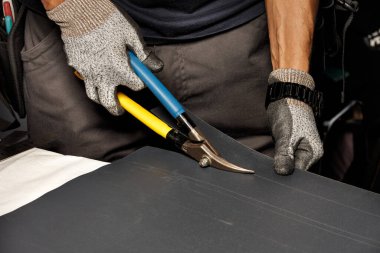 Bir işçinin erkek eli çatıyı su geçirmez hale getirmek için metal makasla çatı demirinden bir yaprak kesti. Kapat, boşluğu kopyala.