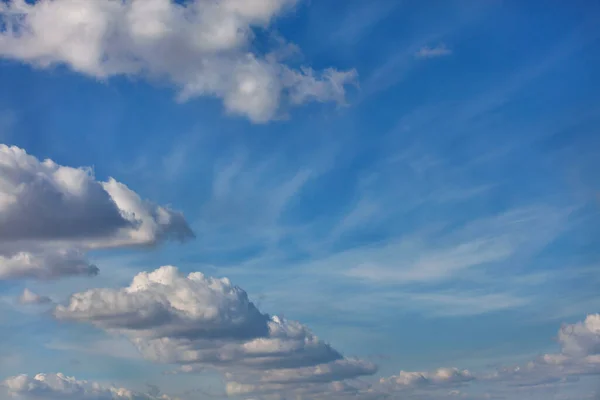 真っ青な空を横切ってリズミカルな半円に浮かぶ緑豊かな白い雲 — ストック写真