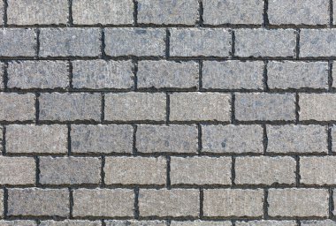 Duvarın yüzeyindeki hoş simetrik desen pürüzlü kenarlı düz dikdörtgen taş fayanslarla çevrili, güneş ışığıyla aydınlatılmış, yüksek çözünürlüklü..