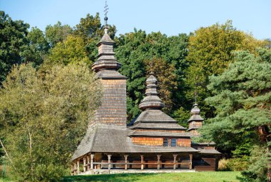 Antik bir Carpathian ahşap kilisesinin ön cephesi. Duvarları oyulmuş ve çatıda yoğun bir ormanın arka planına karşı duran kubbeler varmış..