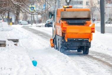 Bir turuncu süpürge, gün boyunca şehrin kaldırımlarındaki karları temizler. Boşluğu kopyala.