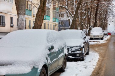Kar kaplı arabaların park ettiği kış sahnesi..