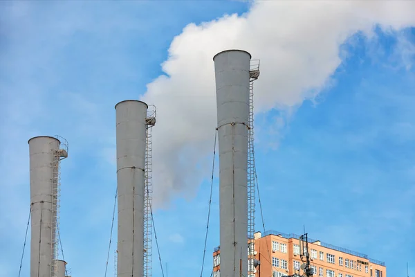 발전소의 굴뚝에서는 주거용 건물의 꼭대기와 하늘의 배경에 대항하여 수증기가 대기중으로 — 스톡 사진