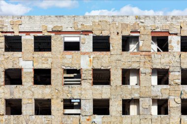 Mavi bulutlu gökyüzüne karşı terk edilmiş eski bir binanın boş pencereleri açılıyor..
