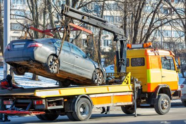 Güneşli bir kış gününde şehir caddesinde bir çekiciye araba yüklemek..