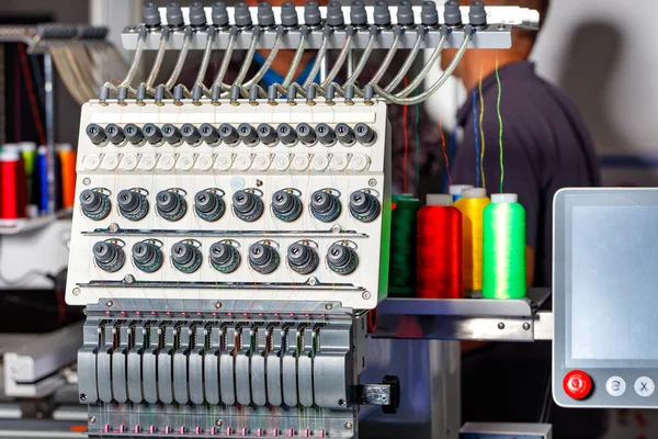 Modern electronic professional embroidery machine using preset programs for embroidery with multi-colored threads. Selective focus. Copy space.