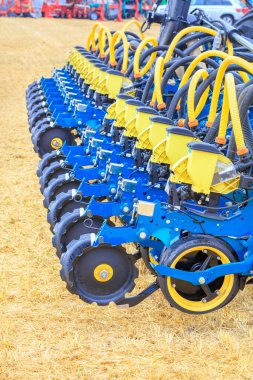 Pnömatik hassas tohum dağılımı için çalışma mekanizmaları olan, sarı bir sakal alanının arka planına karşı çalışan çok satırlı modern bir ekici ve dağıtım boruları. Dikey görüntü. Boşluğu kopyala.