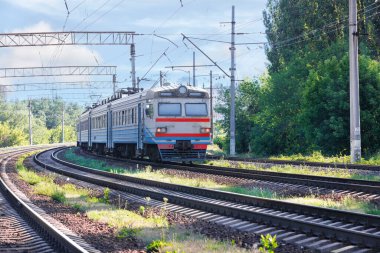 Yolcu eski tren, güneşli bir yaz gününde kentsel alanlardan ayrılarak tren rayları boyunca koşar..