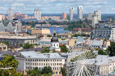 Kyiv 'deki Kontraktova Meydanı' ndaki Podila 'nın tarihi bölgesinde, ufuktaki Obolon yerleşim alanının arka planına karşı dönme dolap. 07.24.22. Kyiv. Ukrayna.