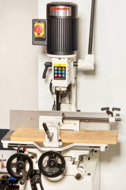 Closeup of an electric vertical milling machine with a powerful motor for processing wood parts in a workshop.
