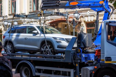 Loading a car on a tow truck on a narrow street of the old city on a sunny summer day.