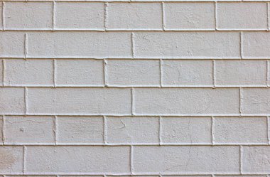 The old brick wall is completely plastered with beige mortar with exposed cement joints.