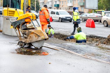 Bir grup yol işçisi kanalizasyon kapaklarını onarıyor ve bir sonbahar günü yeni yollar için eski beton rögar kapaklarını değiştiriyor..