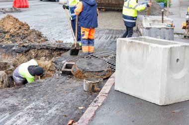 Bir grup yol işçisi kanalizasyon kapaklarını onarıyor ve bir sonbahar günü yeni yollar için eski beton rögar kapaklarını değiştiriyor..