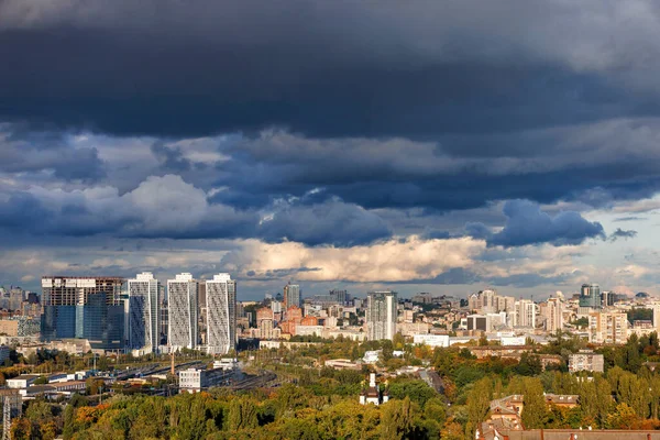 Beautiful cityscape and architecture of residential areas of Kyiv against the backdrop of a stormy sky in the rays of the setting sun. Ukraine.