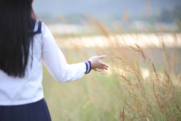 亚洲高中女生手摸青草带日出 — 图库照片