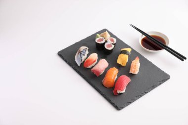Suşi, soya soslu nigiri ve suşi sarmaları ve Japon yemek çubukları beyaz arka planda izole edilmiş.
