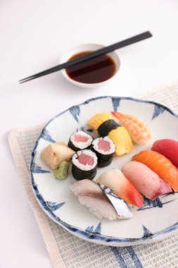 Suşi, soya soslu nigiri ve suşi sarmaları ve Japon yemek çubukları beyaz arka planda izole edilmiş.