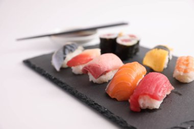 Suşi, soya soslu nigiri ve suşi sarmaları ve Japon yemek çubukları beyaz arka planda izole edilmiş.