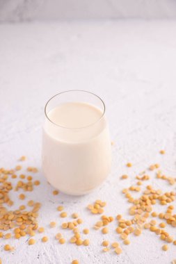 Bardakta soya sütü ve beyaz arka planda soyalı fasulye.