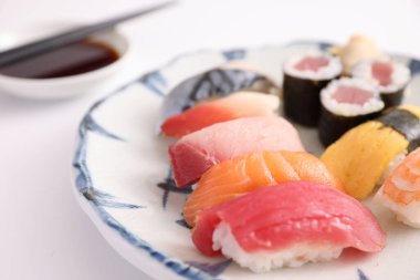 Suşi, soya soslu nigiri ve suşi sarmaları ve Japon yemek çubukları beyaz arka planda izole edilmiş.