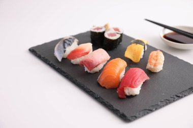 Suşi, soya soslu nigiri ve suşi sarmaları ve Japon yemek çubukları beyaz arka planda izole edilmiş.