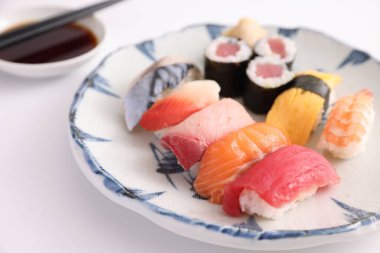 Suşi, soya soslu nigiri ve suşi sarmaları ve Japon yemek çubukları beyaz arka planda izole edilmiş.