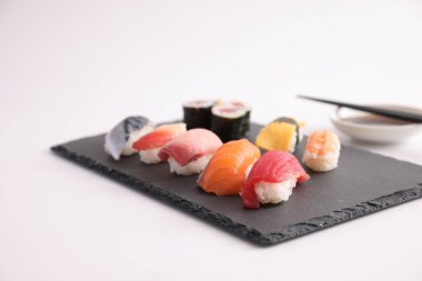 Suşi, soya soslu nigiri ve suşi sarmaları ve Japon yemek çubukları beyaz arka planda izole edilmiş.