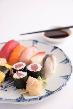 Suşi, soya soslu nigiri ve suşi sarmaları ve Japon yemek çubukları beyaz arka planda izole edilmiş.