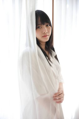 Güzel genç bir kadın sabah beyaz yatak odasında uyanıyor.