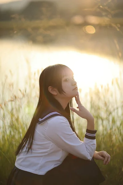 亚洲高中女生坐在那里 看着带着日出的乡村相机 — 图库照片