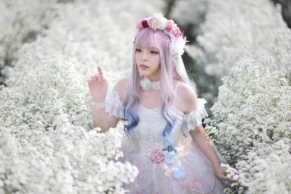 白い花の庭の背景にロリータファッションドレスを持つアジアの若い女性の肖像画 — ストック写真