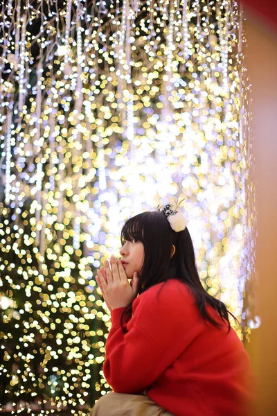 美しいですアジアの若いです女性とともに赤いセーターとともにクリスマスツリーライト — ストック写真