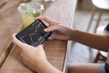 Kafede borsa alım satımı için akıllı telefon kullanan bir kadın, iş konsepti.