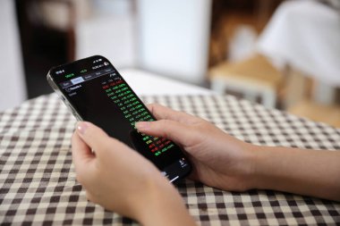 Kafede borsa alım satımı için akıllı telefon kullanan bir kadın, iş konsepti.