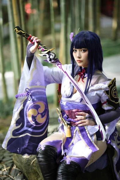 日本花园里一个穿着武士服装的年轻漂亮女子游戏的肖像 — 图库照片
