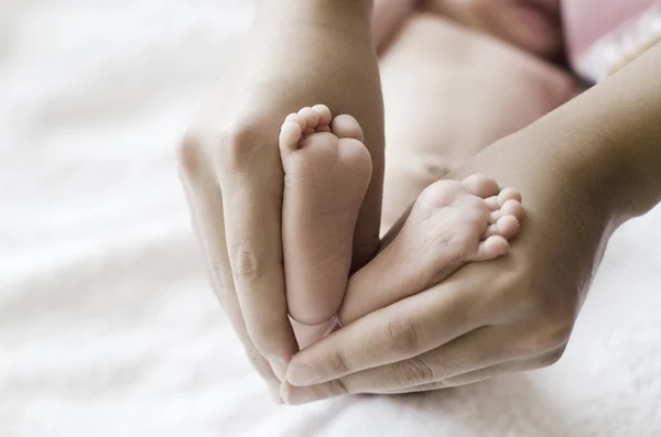 Babyfuß in den Händen der Mutter lizenzfreie Stockbilder