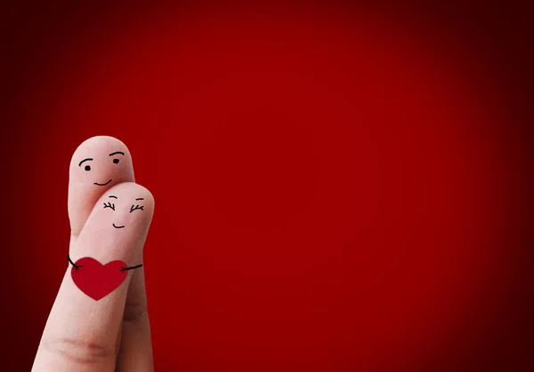 Feliz pareja enamorada de sonriente pintado sosteniendo el corazón rojo — Foto de Stock
