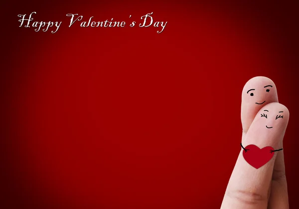 Happy couple in love with painted smiley holding red heart — Stock Photo, Image