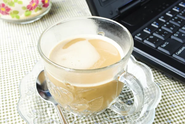 Une tasse de café et un ordinateur portable — Photo