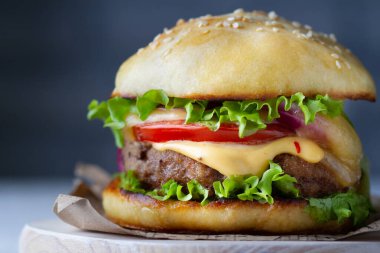 Hamburger, pirzola, domates, marul ve peynir, akan sos.