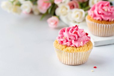 Cupcakes with pink cream with hearts and flowers, copy space