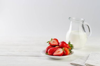 Beyaz arka planda sütlü çilekler, masa, kopyalama alanı