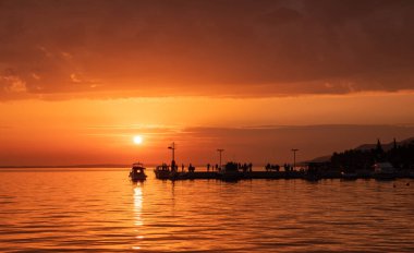 Deniz kıyısında dramatik bir yaz günbatımı. İnsanlar akşamın tadını çıkarıyor..